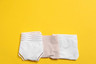 Stylish folded women's underwear on yellow background, flat lay. Space for text