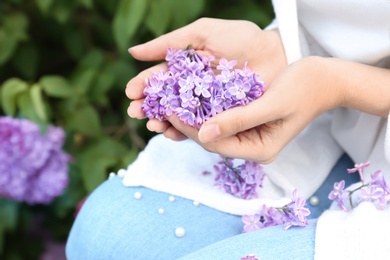 Young woman with blossoming lilac outdoors on spring day