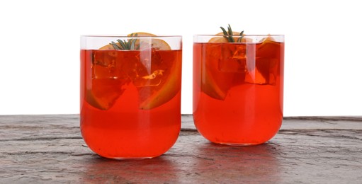 Photo of Aperol spritz cocktail, orange slices and rosemary in glasses on grey textured table against white background