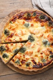 Photo of Delicious homemade quiche with salmon and broccoli on wooden table, top view