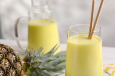 Tasty pineapple smoothie on white table, closeup. Space for text