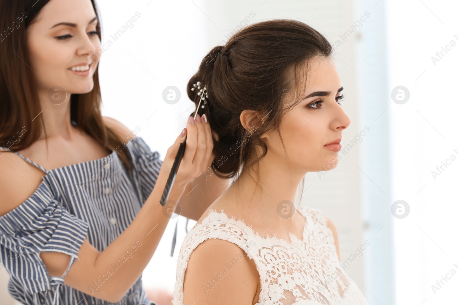 Photo of Professional hairdresser working with young woman in salon