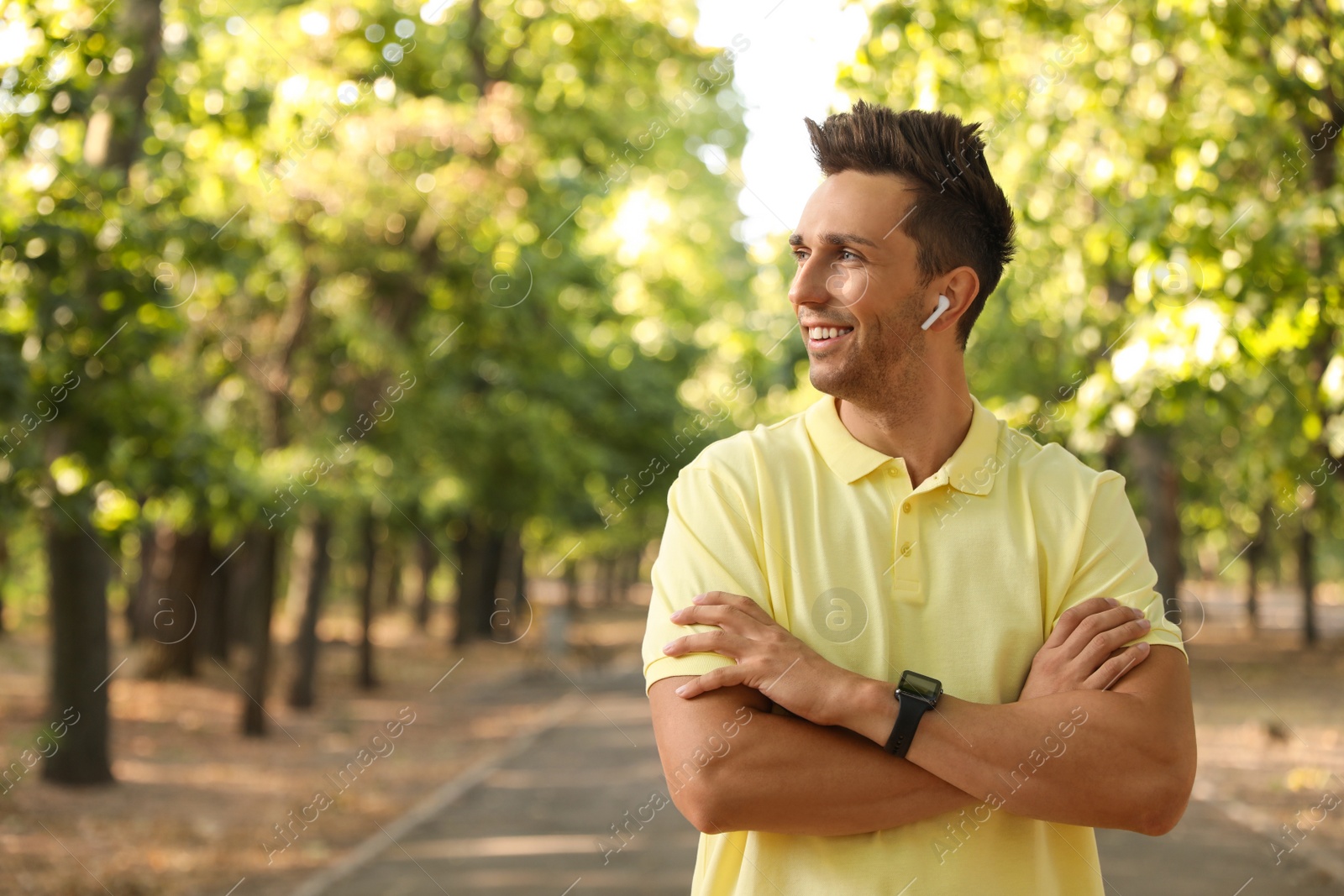 Photo of Young man with wireless earphones in park