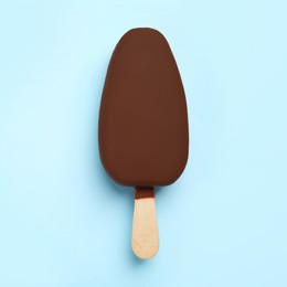 Photo of Ice cream glazed in chocolate on light blue background, top view