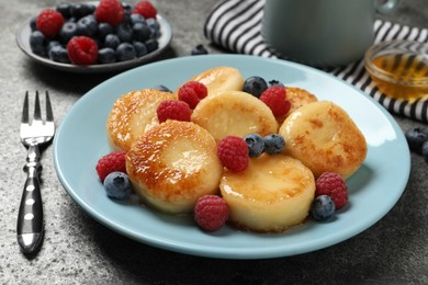 Photo of Delicious cottage cheese pancakes with fresh berries and honey on grey table