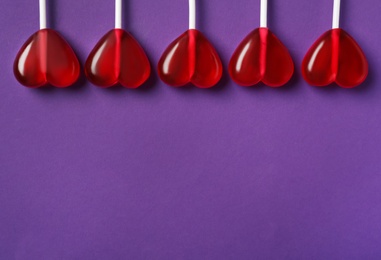 Photo of Sweet heart shaped lollipops on purple background, flat lay with space for text. Valentine's day celebration