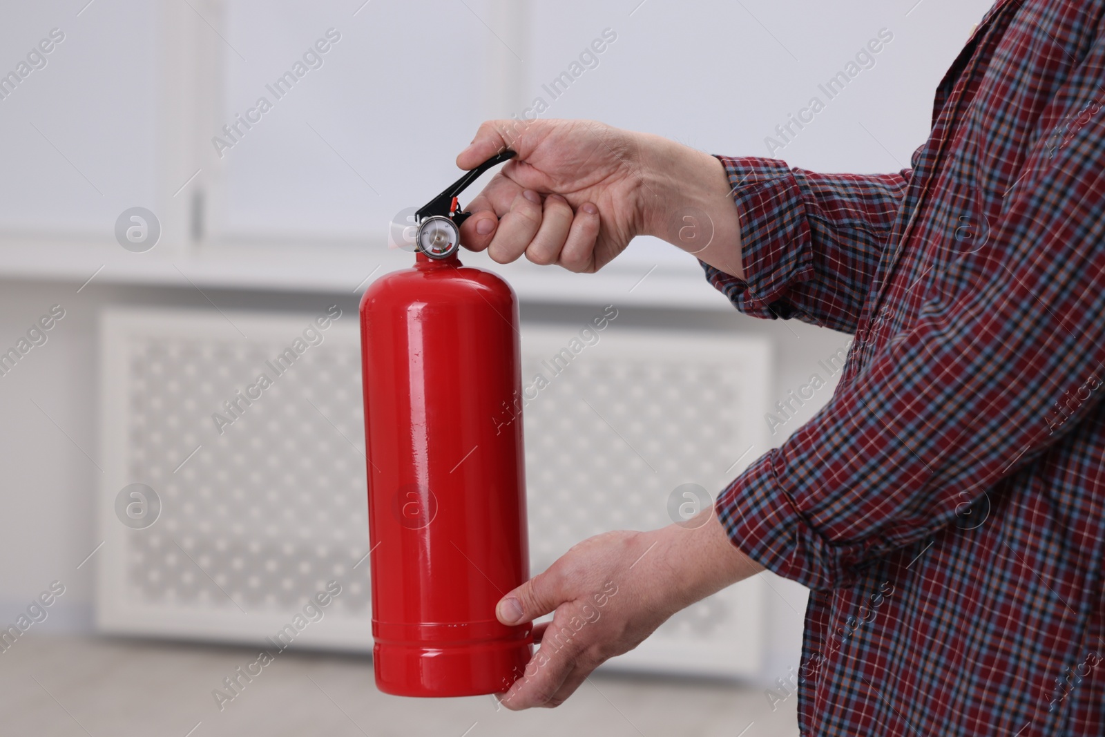 Photo of Man with one fire extinguisher indoors, closeup