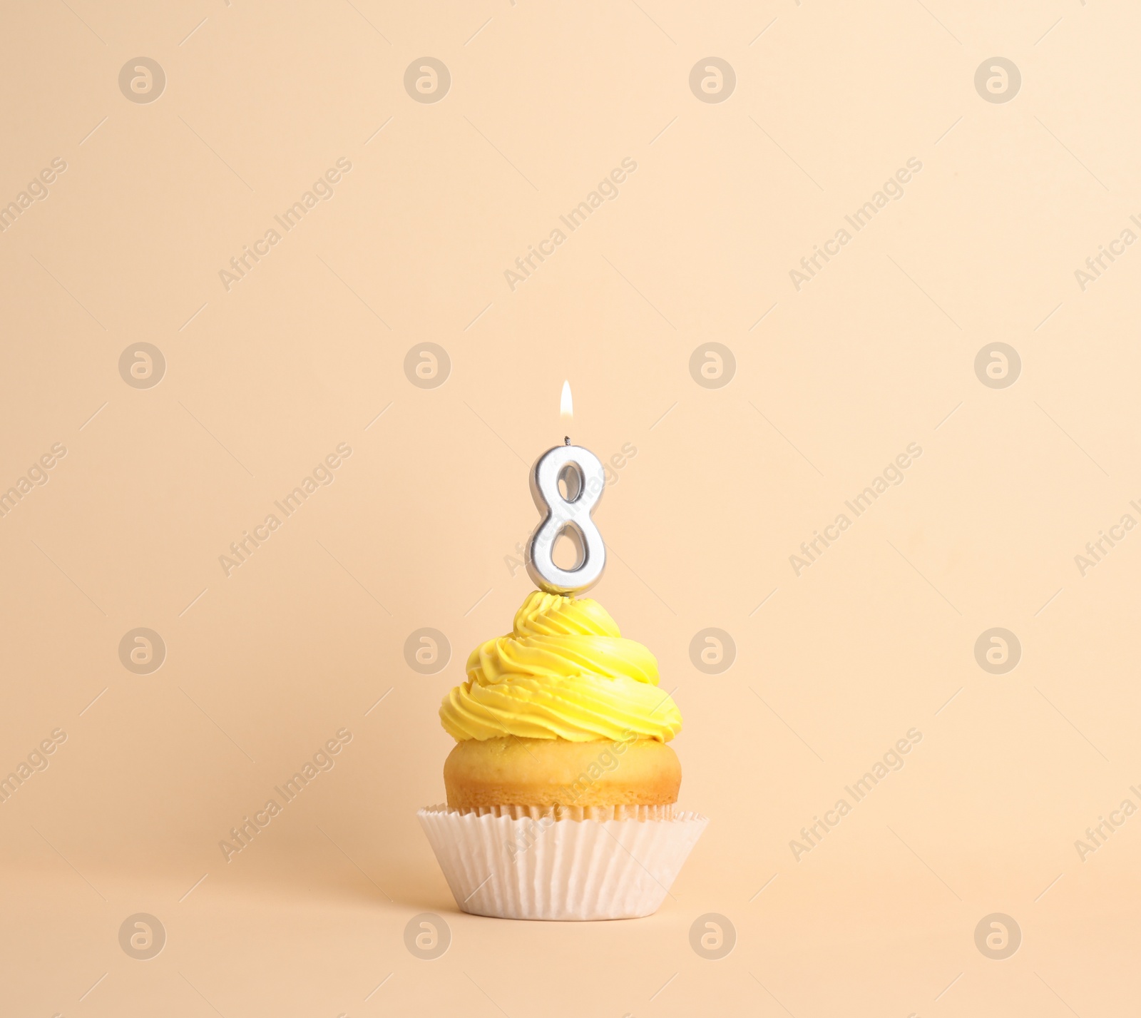 Photo of Birthday cupcake with number eight candle on beige background