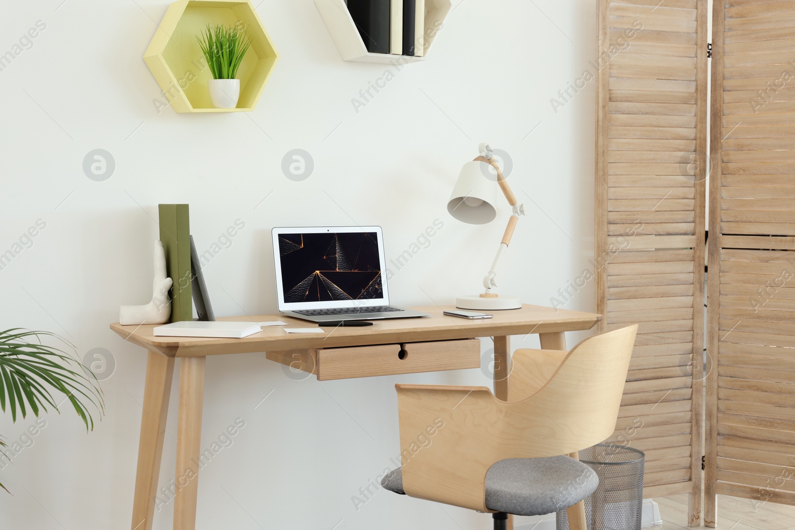 Photo of Cozy workspace with modern laptop on desk and comfortable chair at home