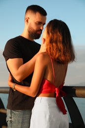 Happy young couple kissing on sea embankment