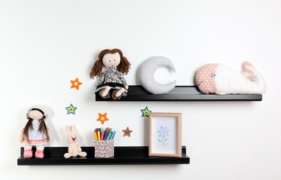 Photo of Cute toys and picture on shelves in child room