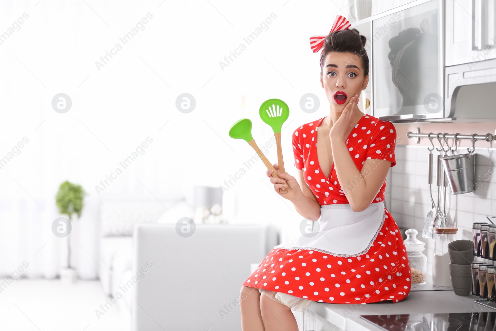 Photo of Funny young housewife with cooking utensils in kitchen