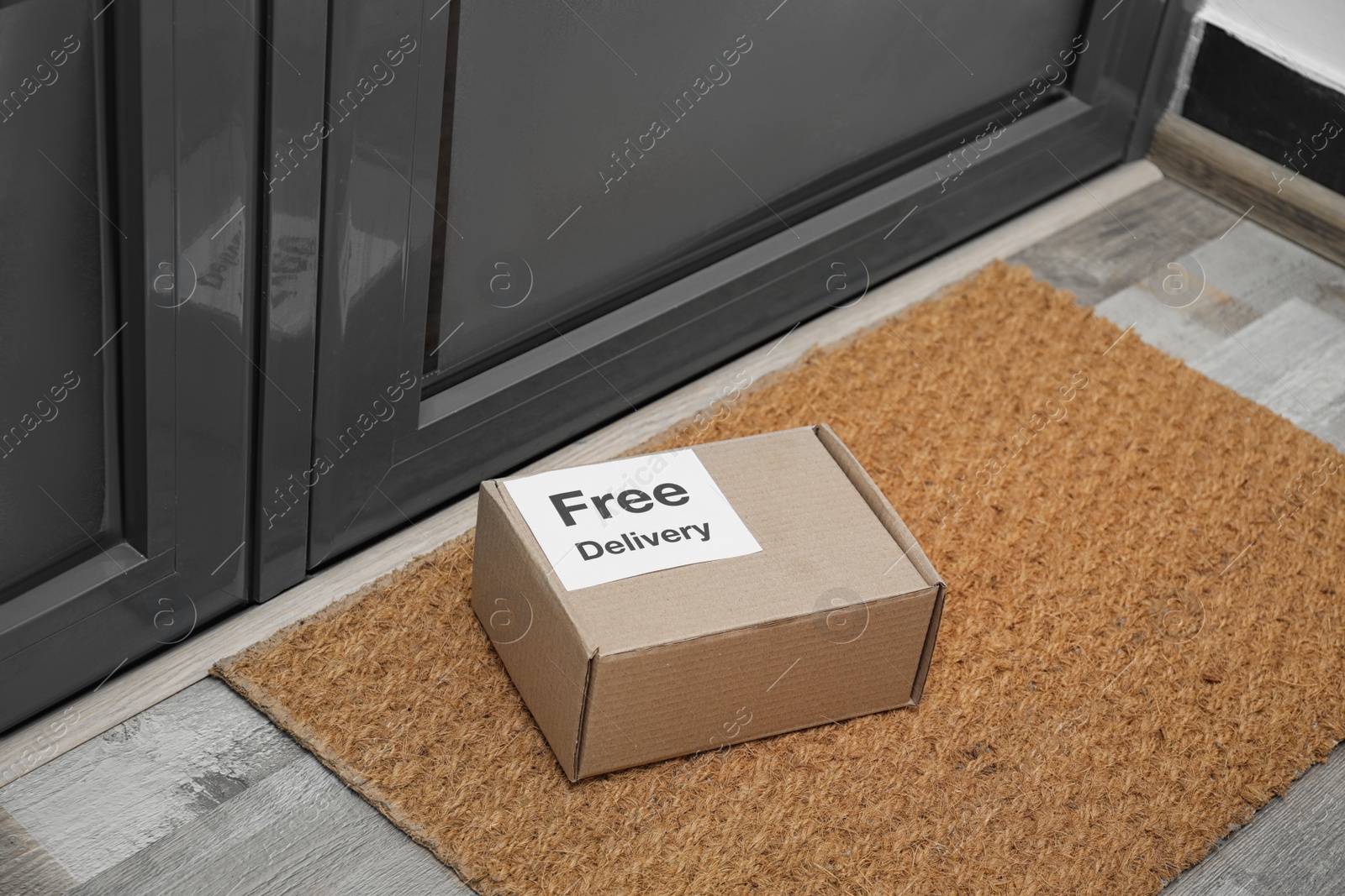 Photo of Parcel with sticker Free Delivery on rug indoors. Courier service