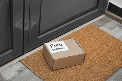 Photo of Parcel with sticker Free Delivery on rug indoors. Courier service