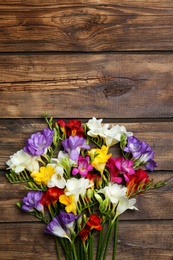 Photo of Beautiful freesia flowers on wooden background