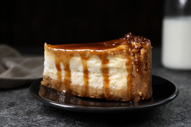 Piece of delicious cake with caramel served on grey table