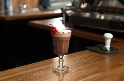 Photo of Glass of coffee drink with cherry and marshmallow on bar counter