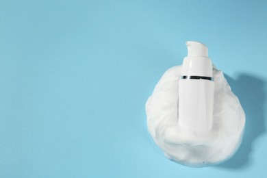 Photo of Bottle with cleansing foam on light blue background, top view and space for text. Cosmetic product