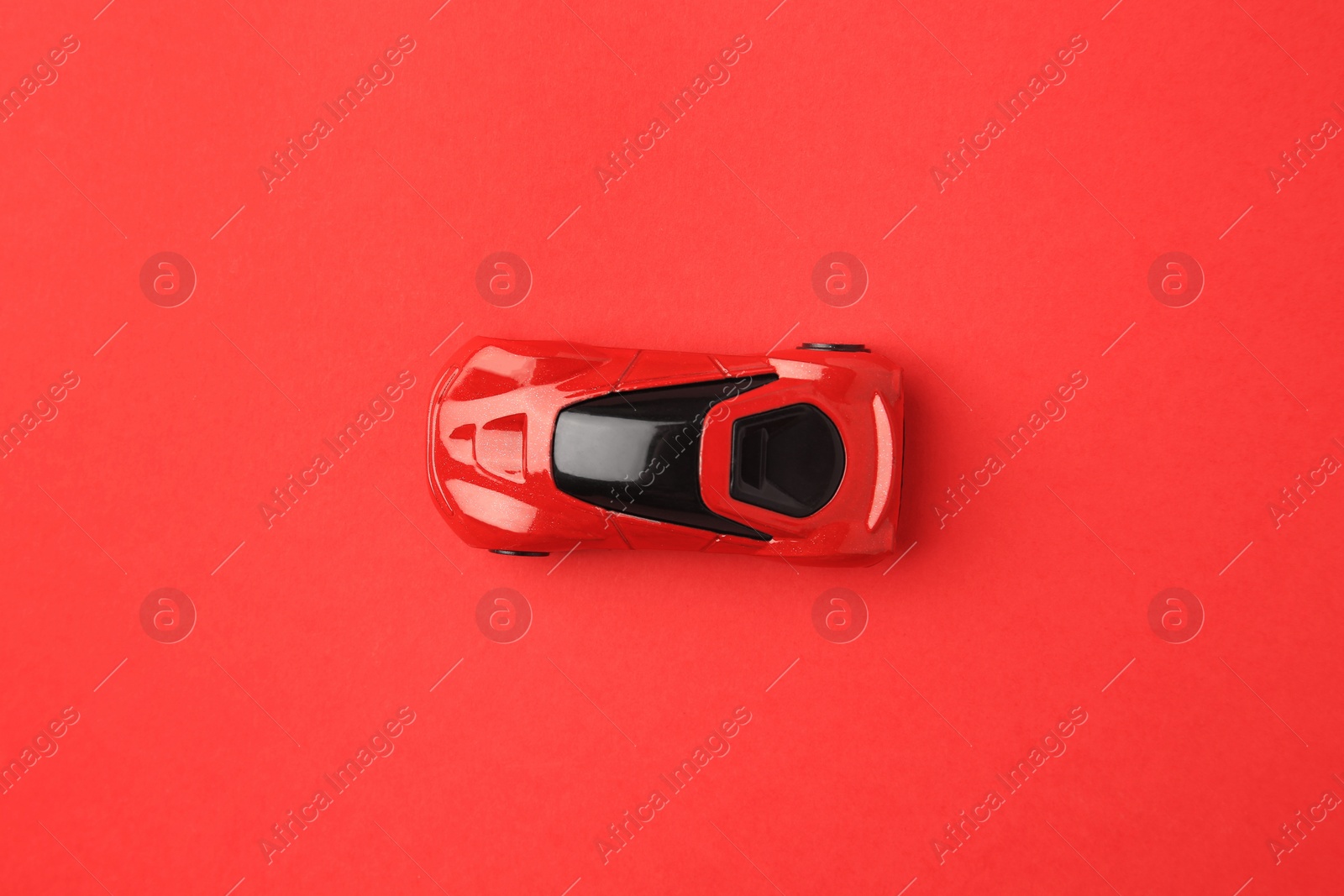 Photo of One bright car on red background, top view