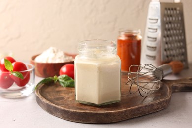 Photo of Pizza dough starter in glass jar, products and whisk on gray table