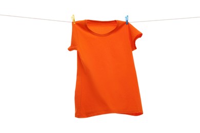 Photo of One orange t-shirt drying on washing line isolated on white