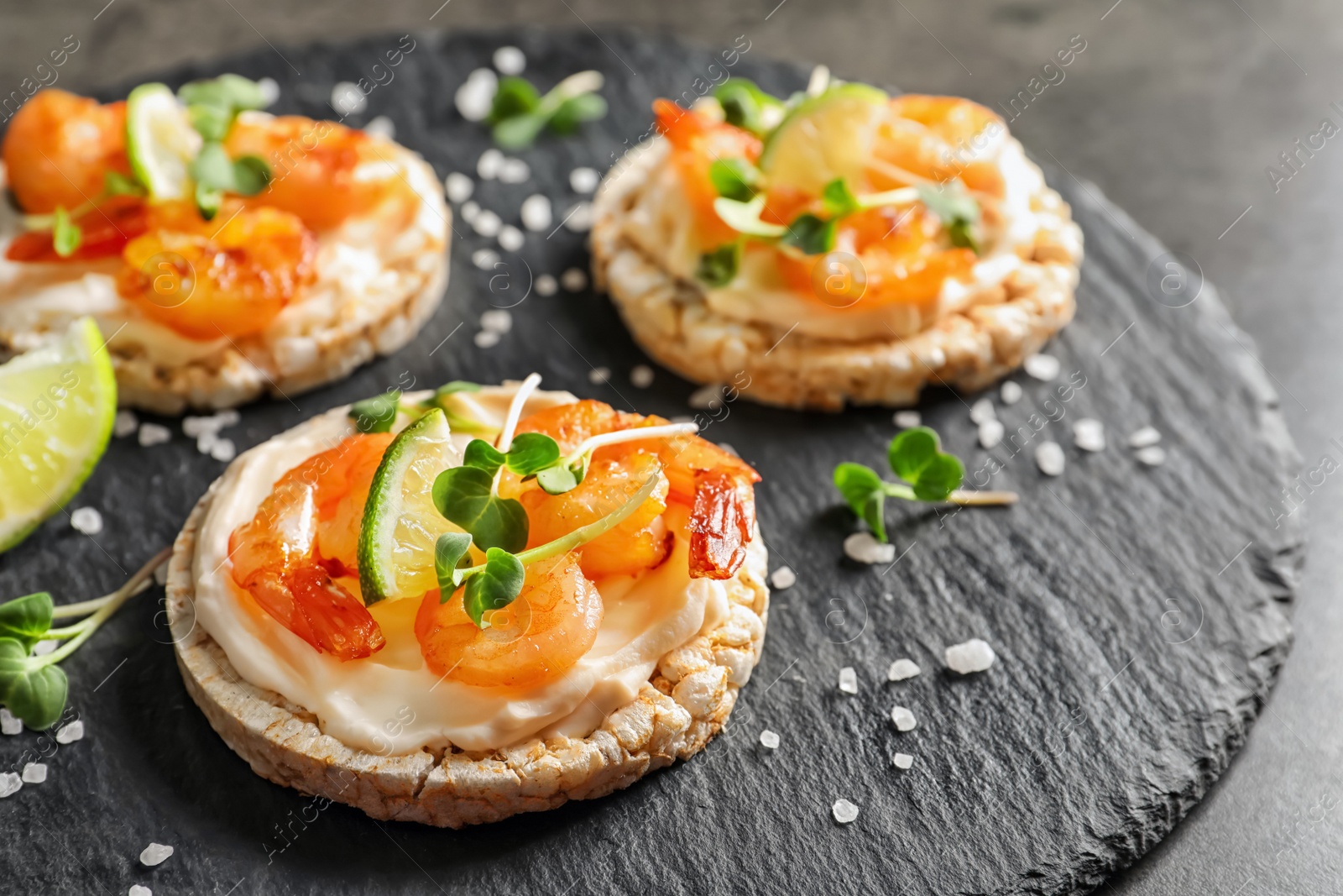 Photo of Delicious small sandwiches with shrimps on slate plate