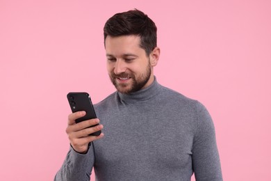 Photo of Happy man using smartphone on pink background