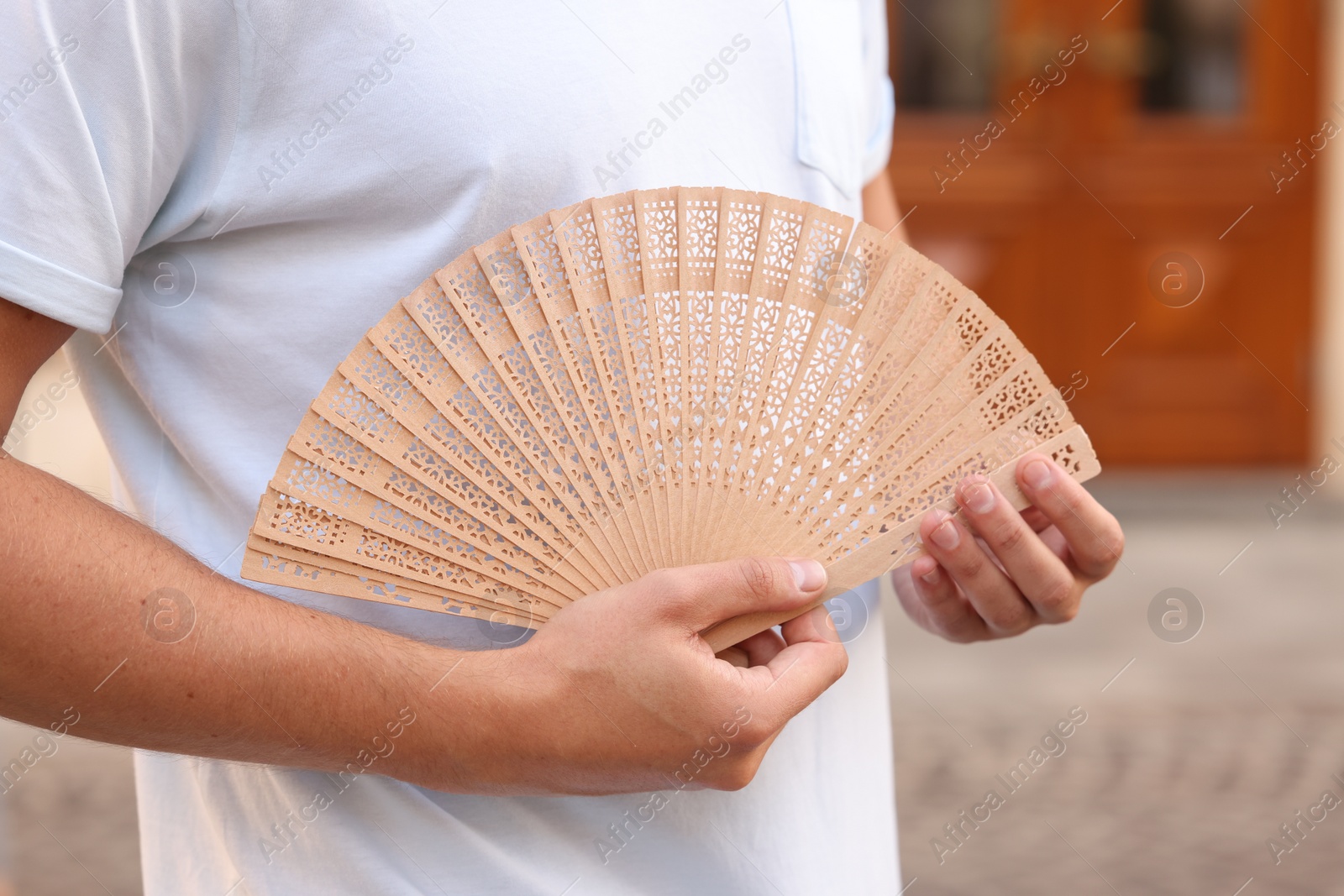 Photo of Man with hand fan outdoors, closeup view