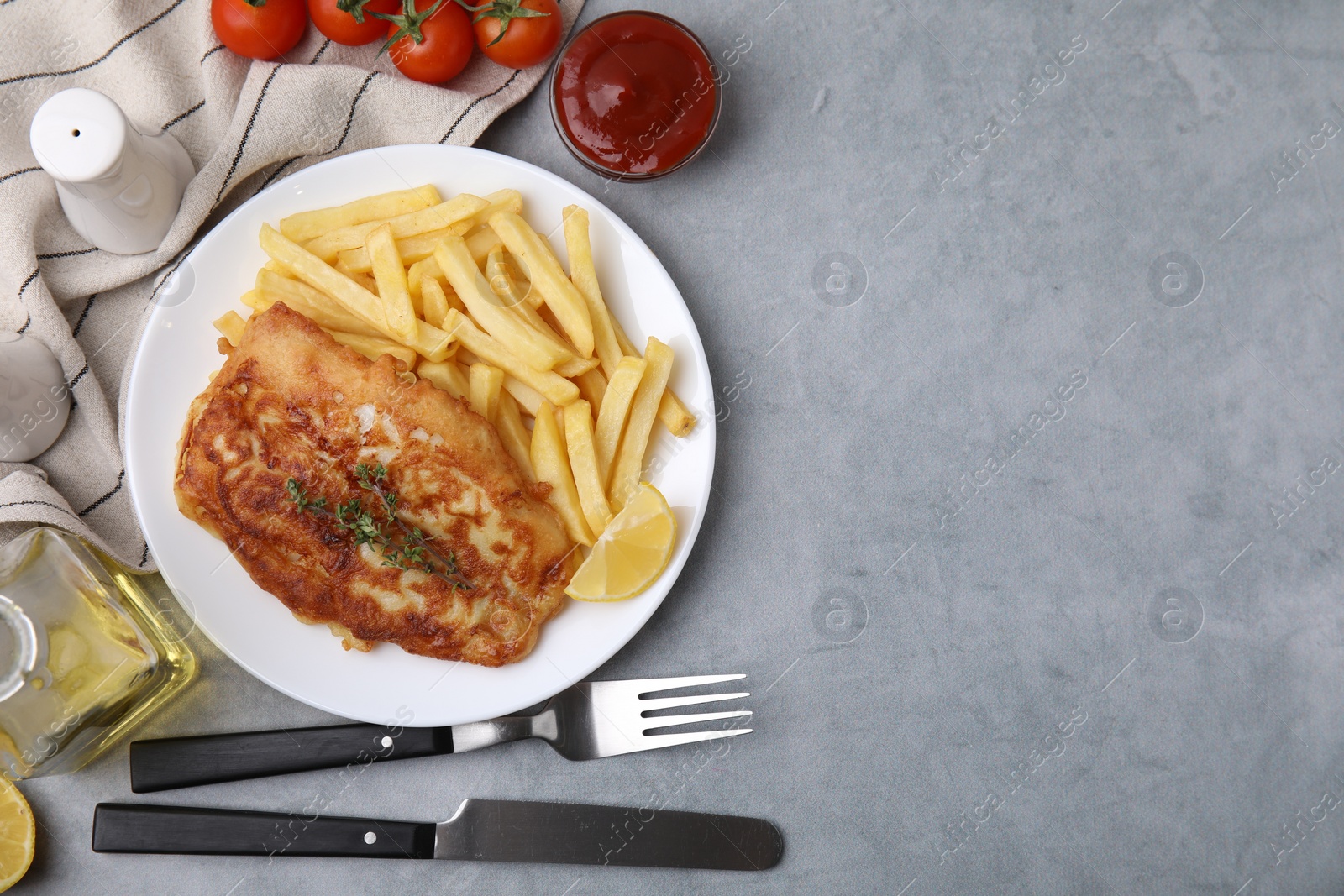 Photo of Tasty soda water battered fish, potato chips and lemon slice served on light grey table, flat lay. Space for text