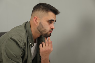 Photo of Portrait of sad man near light grey wall. Space for text