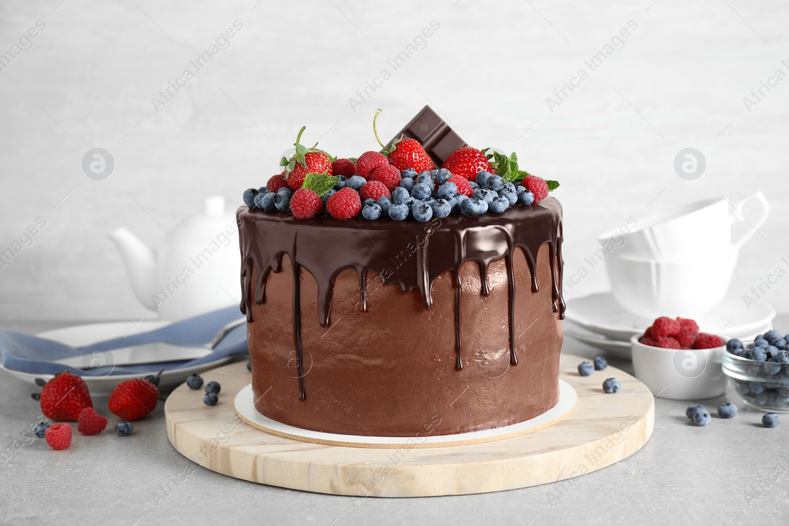 Photo of Freshly made delicious chocolate cake decorated with berries on white table