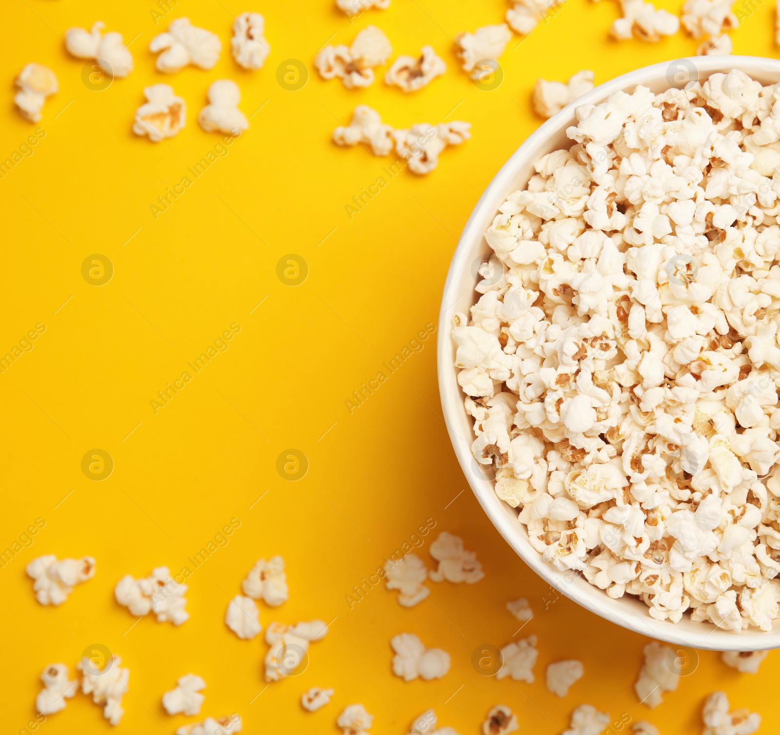 Photo of Paper bucket with tasty fresh popcorn on color background, top view