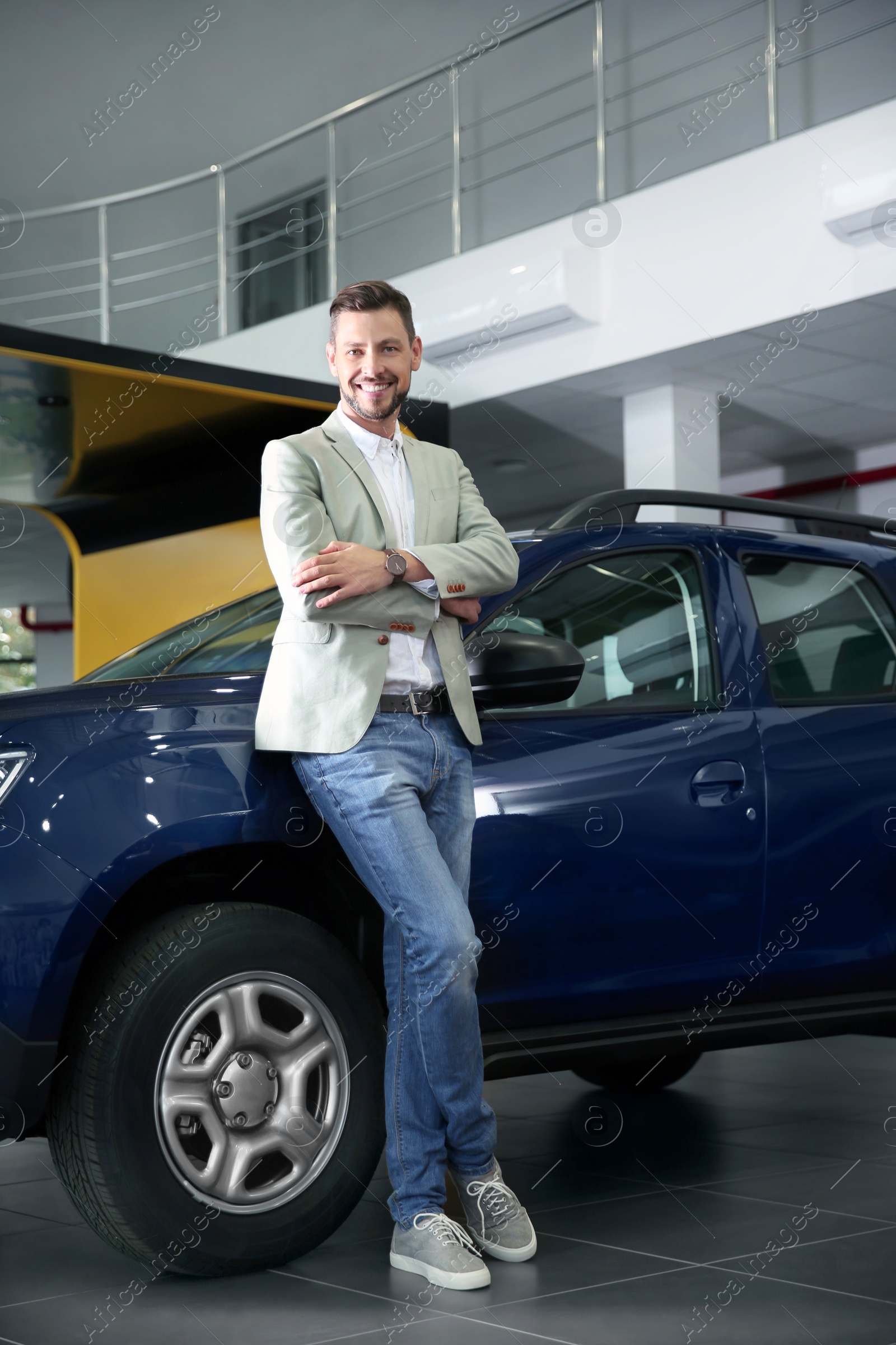 Photo of Man near new car in modern auto dealership