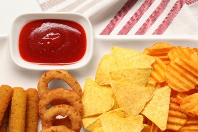 Photo of Different delicious fast food served with ketchup on white table, flat lay