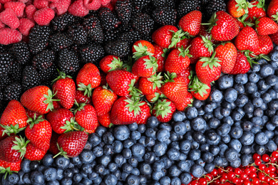 Mix of different ripe tasty berries as background, top view