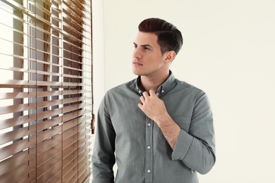 Portrait of handsome man at window indoors