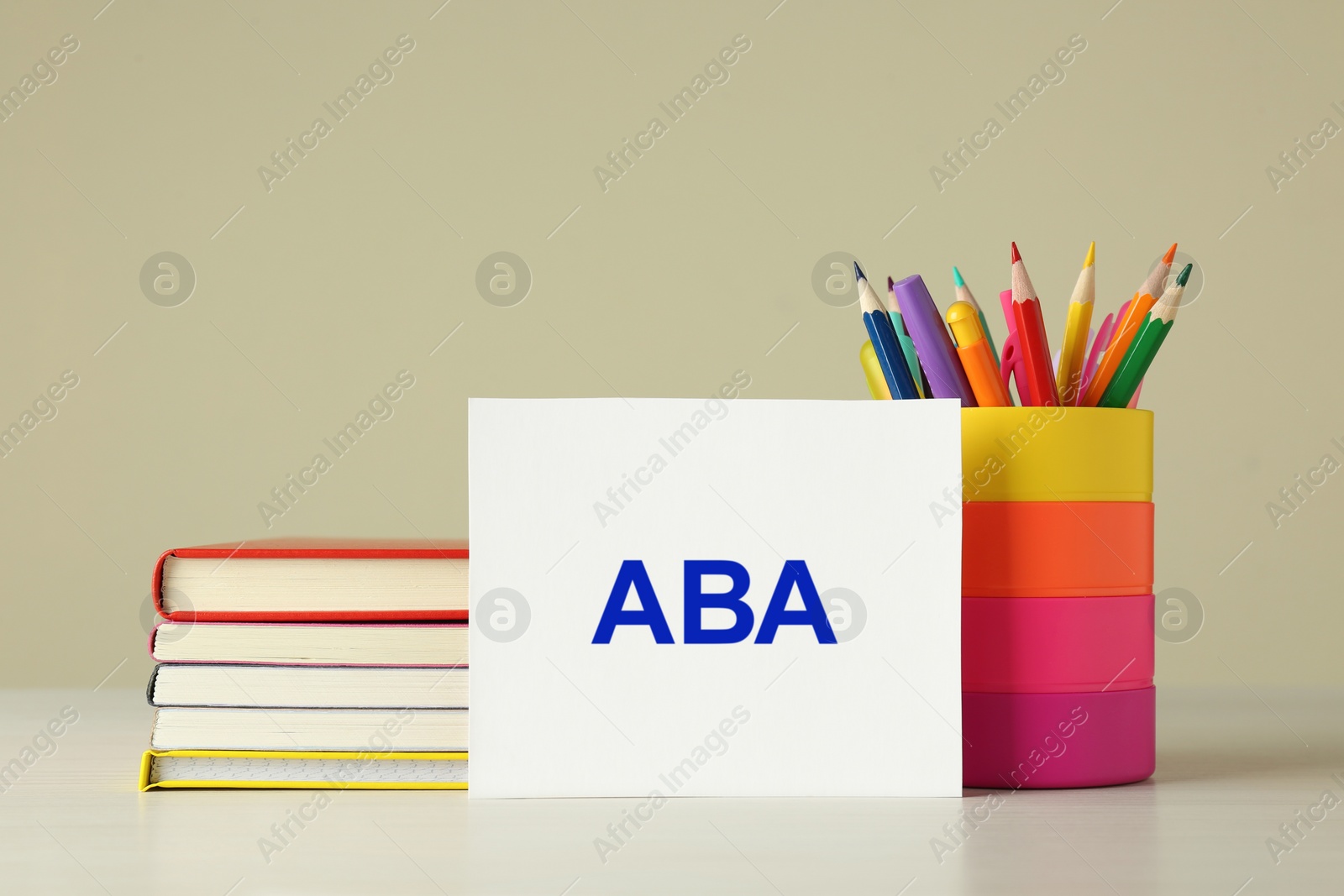 Photo of Set of stationery and card with abbreviation ABA (Applied Behavior Analysis) on wooden table against beige background
