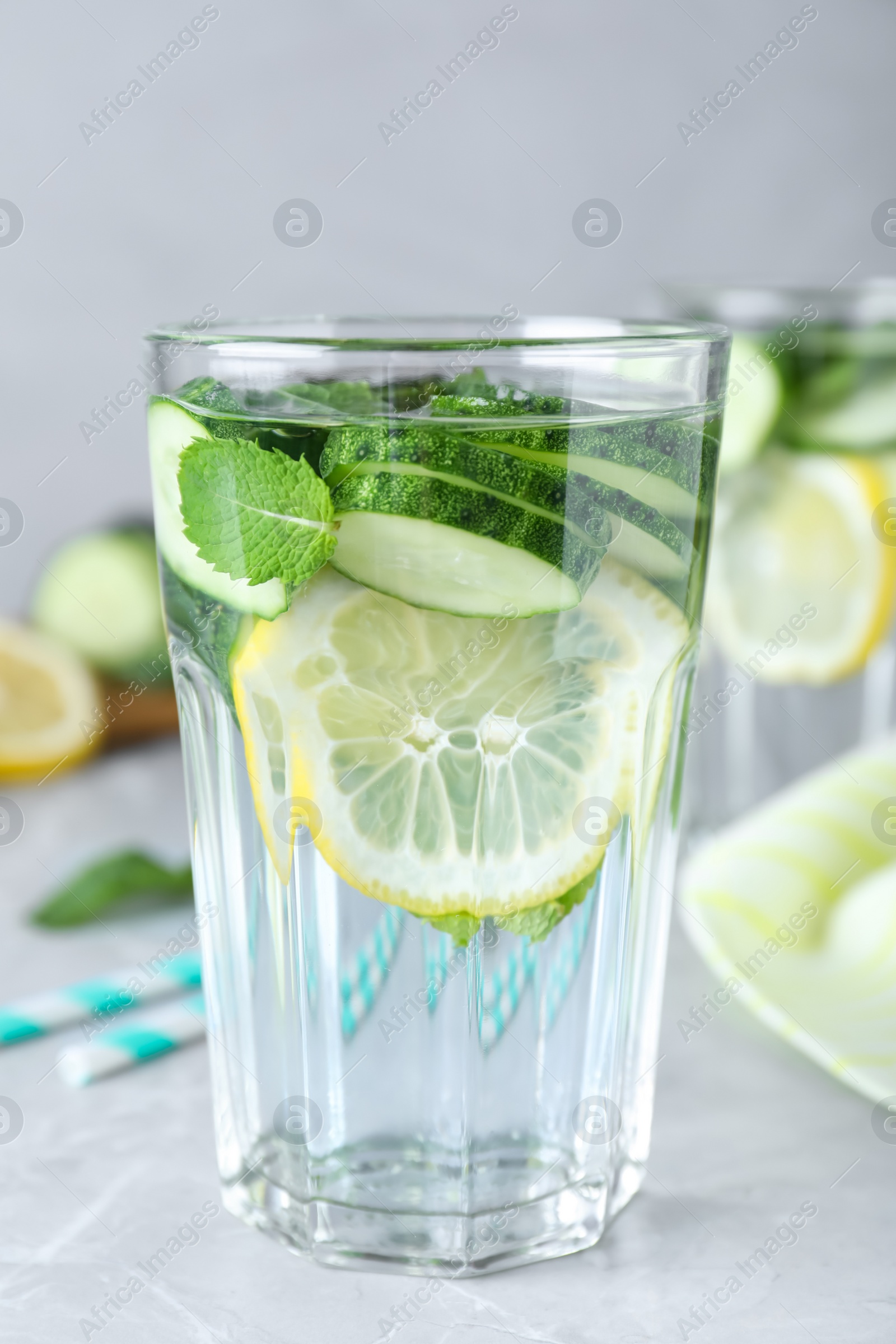 Photo of Refreshing water with cucumber, lemon and mint on light grey table, closeup
