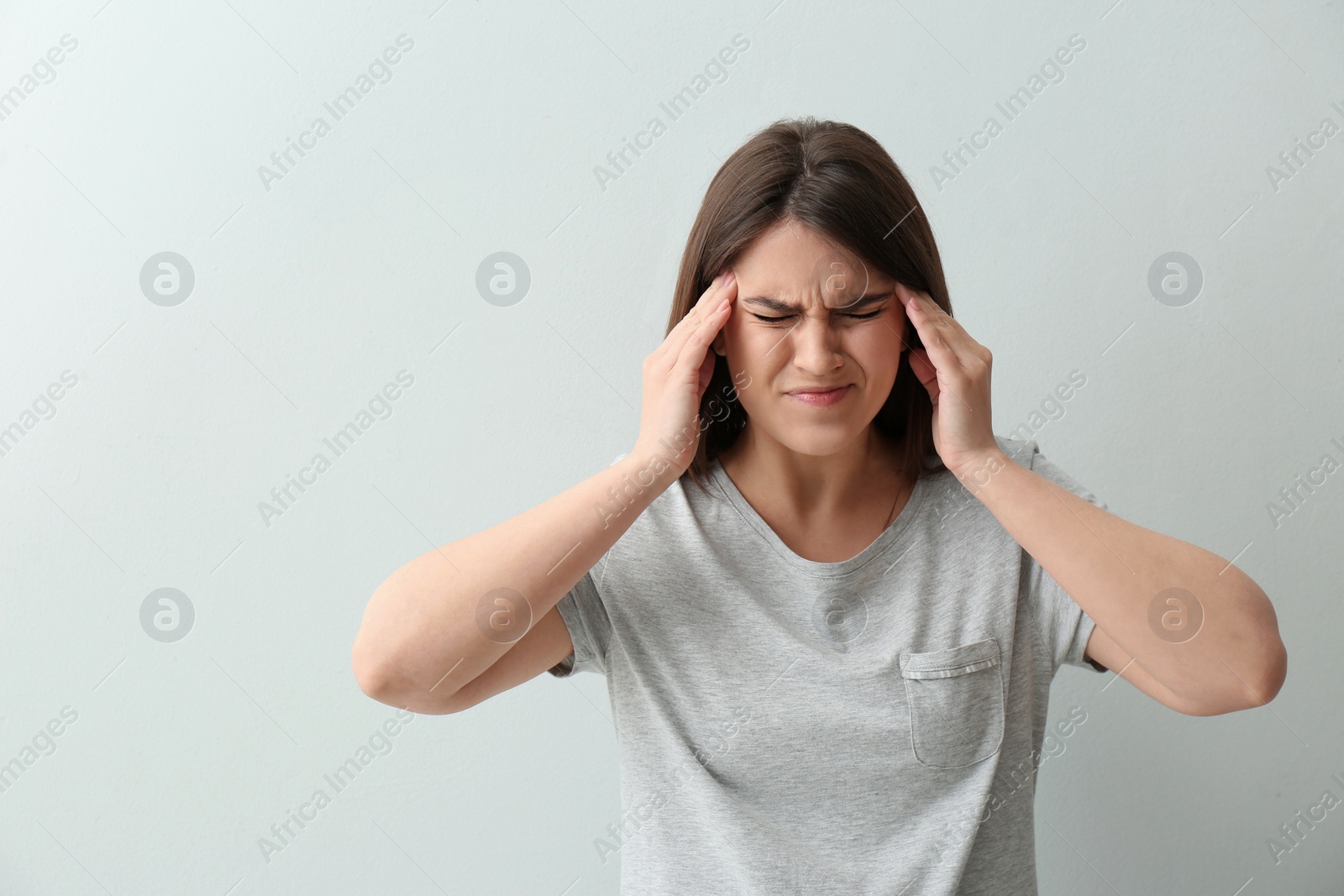 Photo of Young woman suffering from migraine on white background