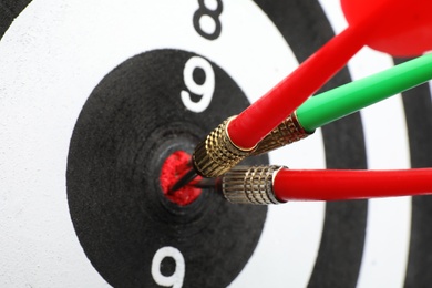 Photo of Dart board with color arrows hitting target, closeup