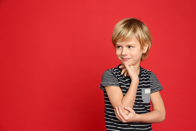 Portrait of emotional little boy on red background. Space for text