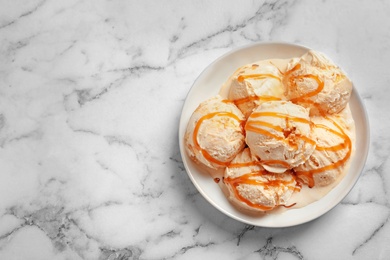 Photo of Tasty ice cream with caramel sauce on plate, top view