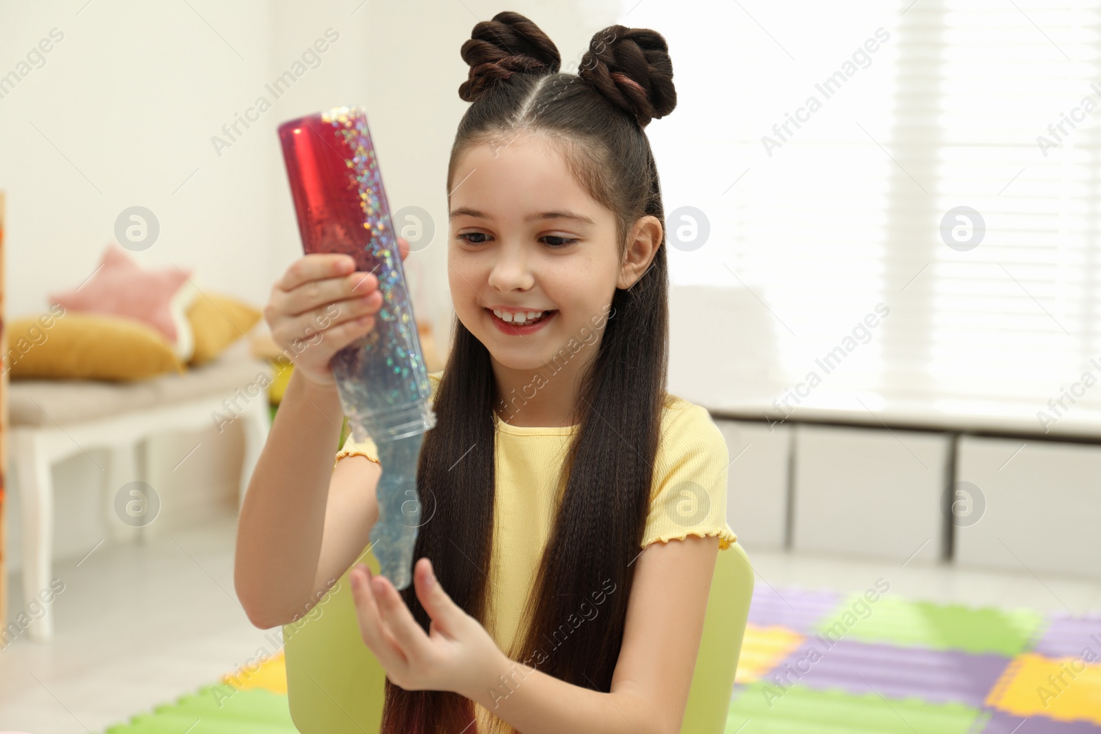 Photo of Little girl playing with slime in room