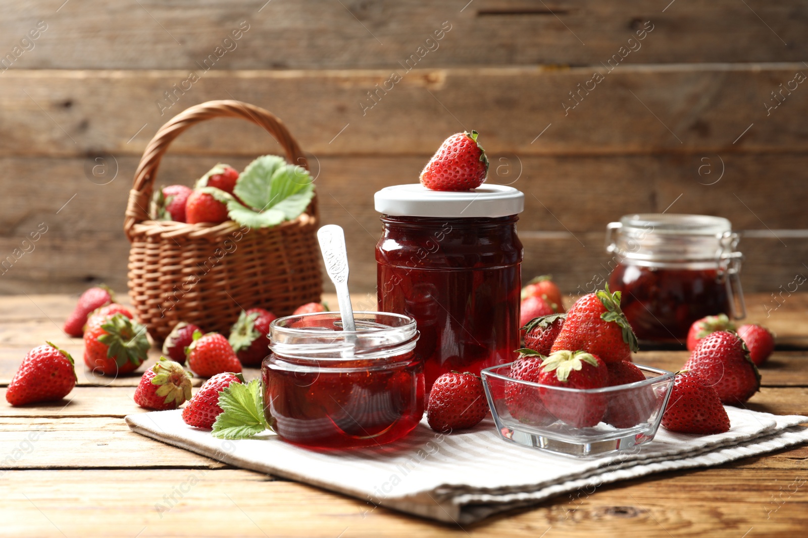 Photo of Delicious pickled strawberry jam and fresh berries on wooden table