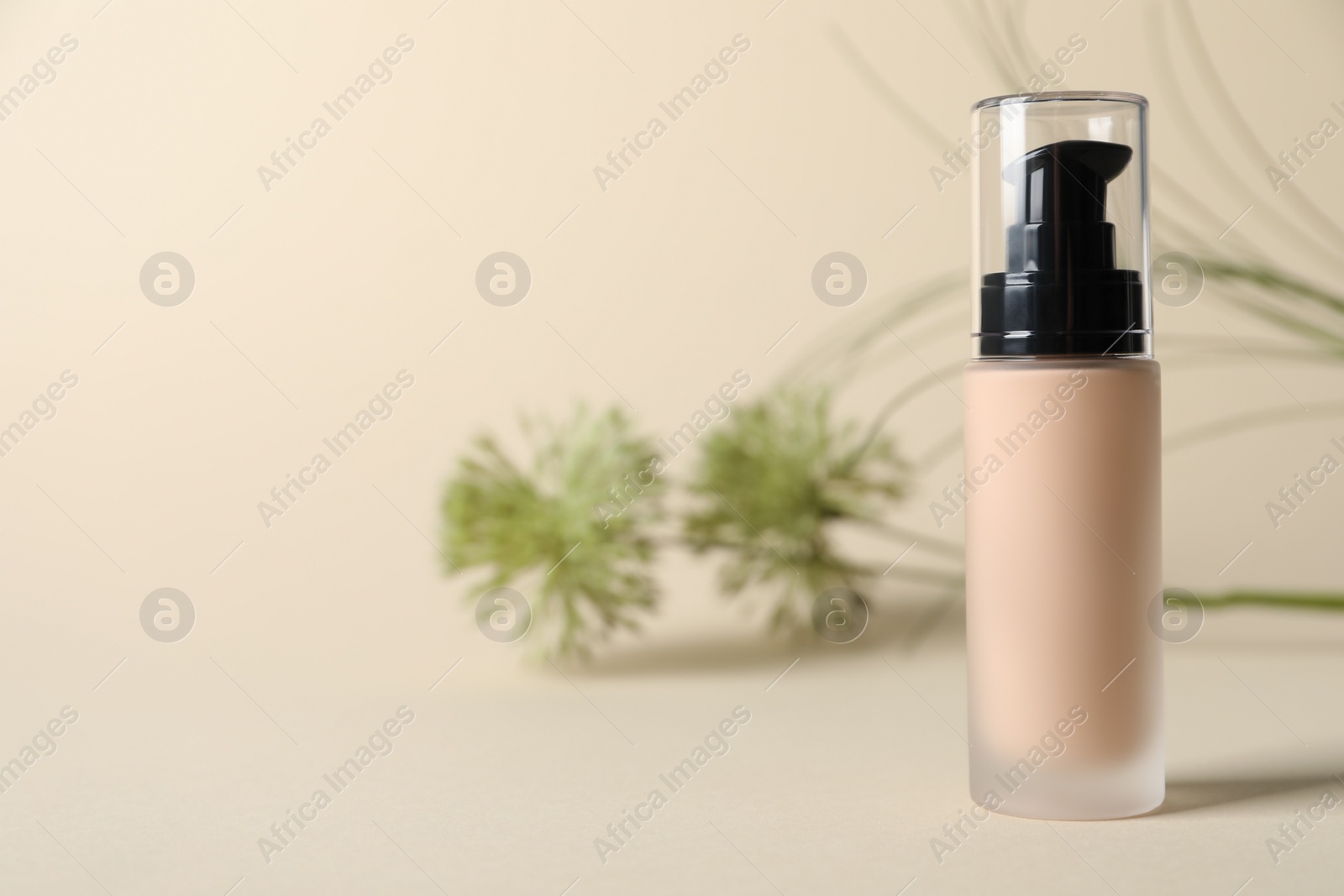Photo of Bottle of skin foundation on beige background, space for text. Makeup product