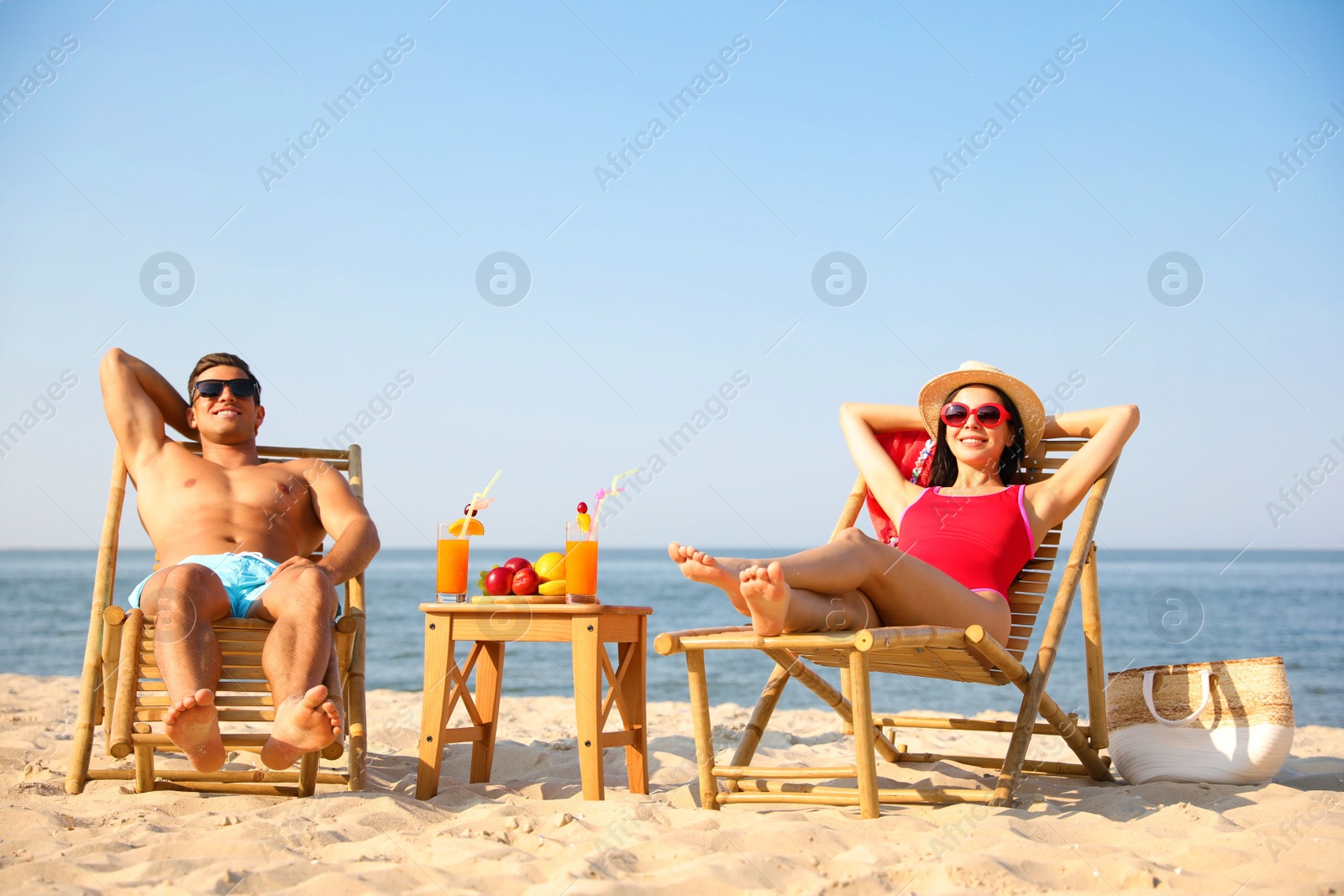 Photo of Happy couple resting on sunny beach at resort