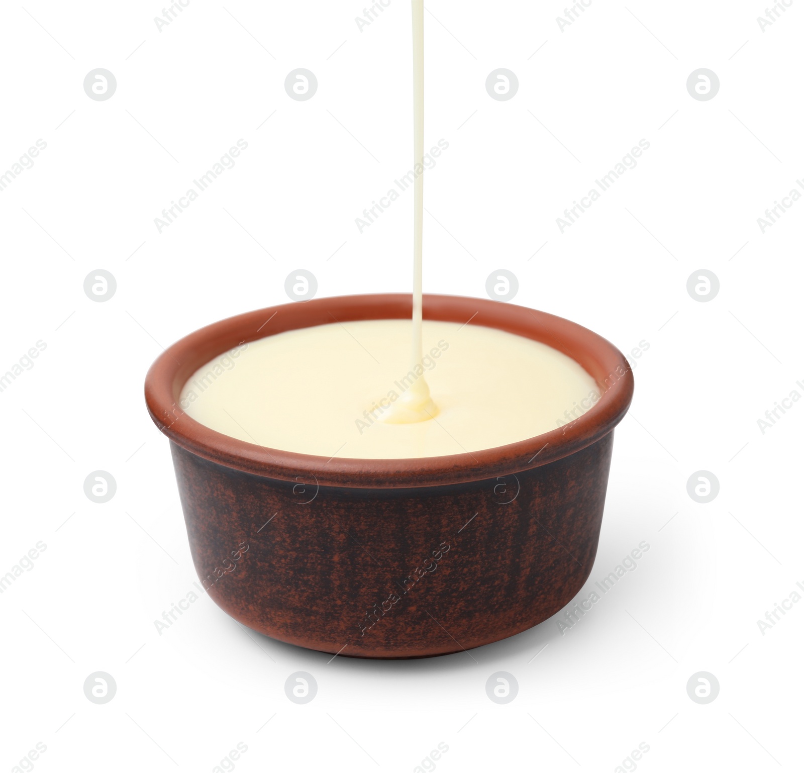 Photo of Pouring condensed milk into bowl isolated on white