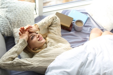 Beautiful young woman awaking and smiling at home, above view. Winter atmosphere