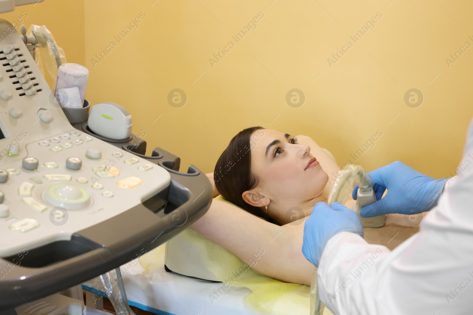 Photo of Mammologist conducting ultrasound examination of woman's breast in clinic, closeup