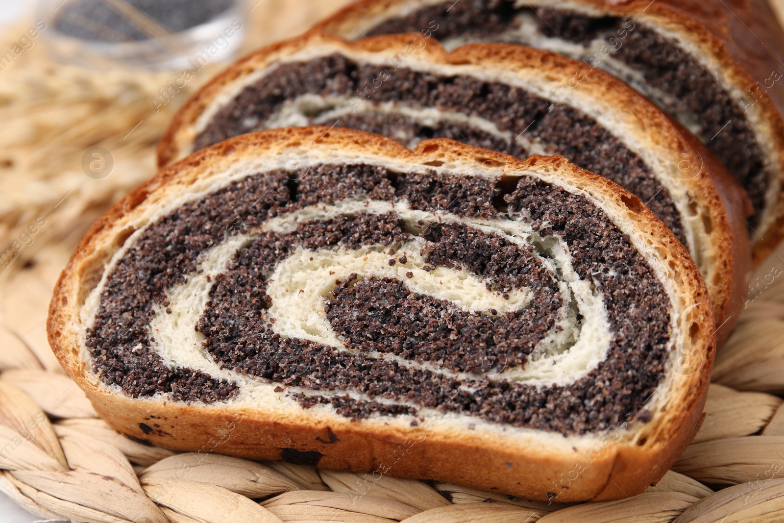 Photo of Cut poppy seed roll on wicker mat, closeup. Tasty cake